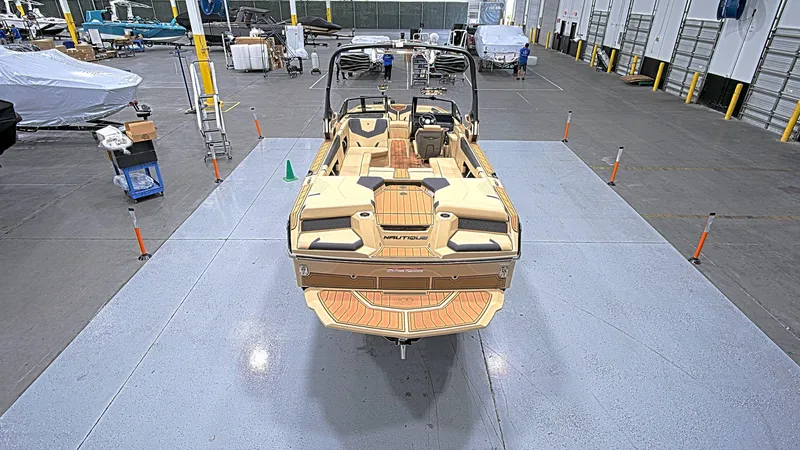  Yacht Photos Pics 2025 Nautique GS24 boat in a spacious indoor facility, showcasing its sleek design.