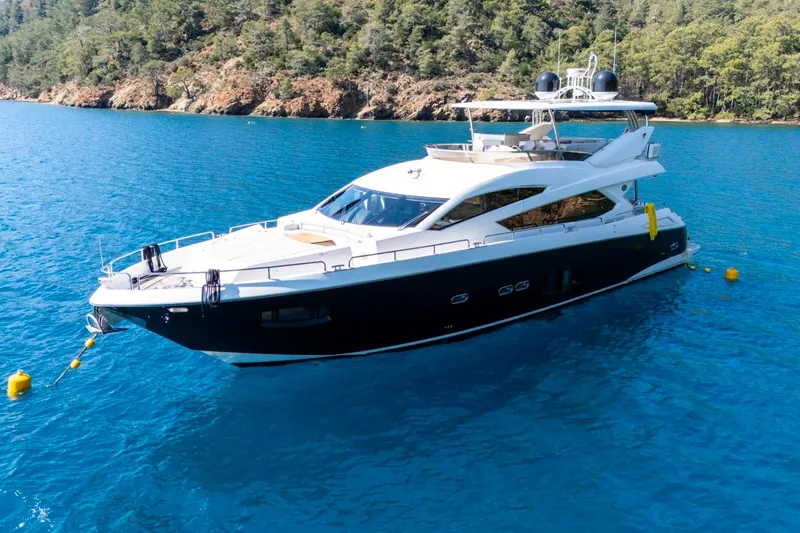  Yacht Photos Pics Luxurious 2011 Sunseeker 80 Yacht anchored in clear blue waters near a forested coastline.