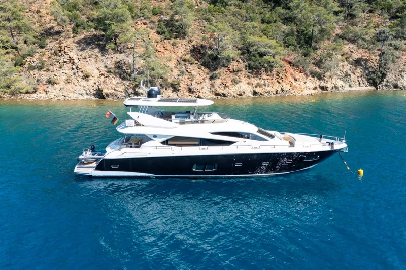  Yacht Photos Pics Luxurious 2011 Sunseeker 80 Yacht anchored in clear blue waters near a rocky coastline.
