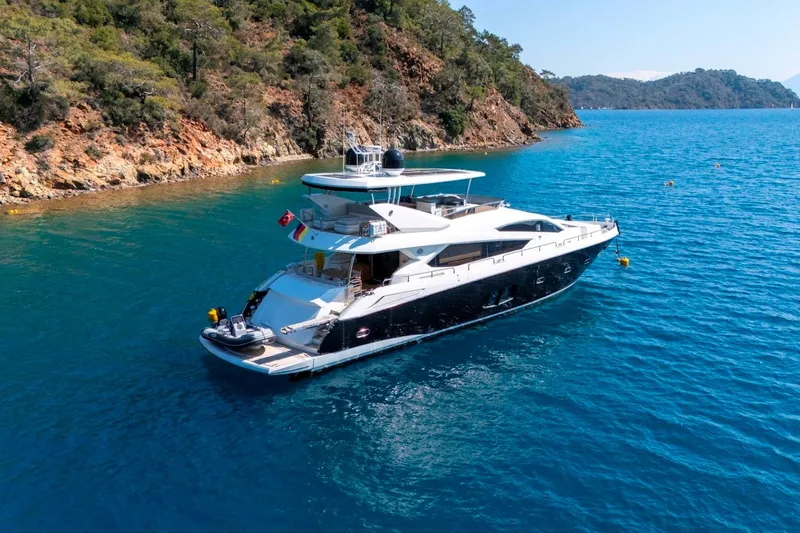  Yacht Photos Pics Luxurious 2011 Sunseeker 80 Yacht cruising in clear blue waters near a rocky coastline.