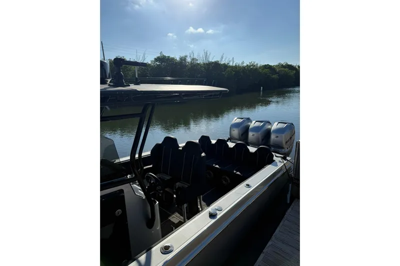  Yacht Photos Pics 2006 Lazer 40 boat with multiple outboard engines docked by a serene river.