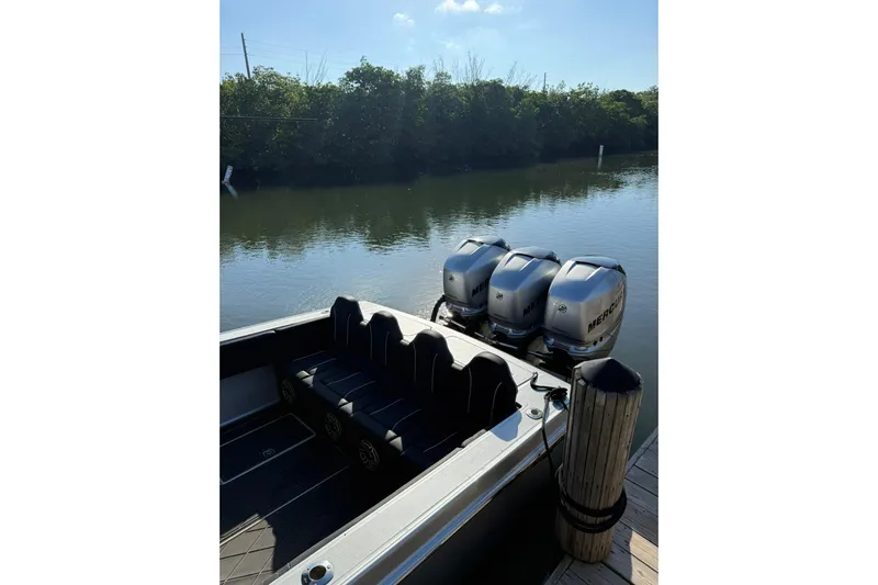  Yacht Photos Pics 2006 Lazer 40 boat with triple Mercury engines docked by a calm river.