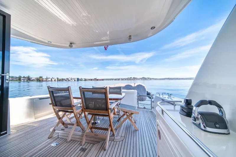 Escape Yacht Photos Pics Luxury Maritimo M58 yacht deck with wooden chairs, ocean view, and clear blue sky.