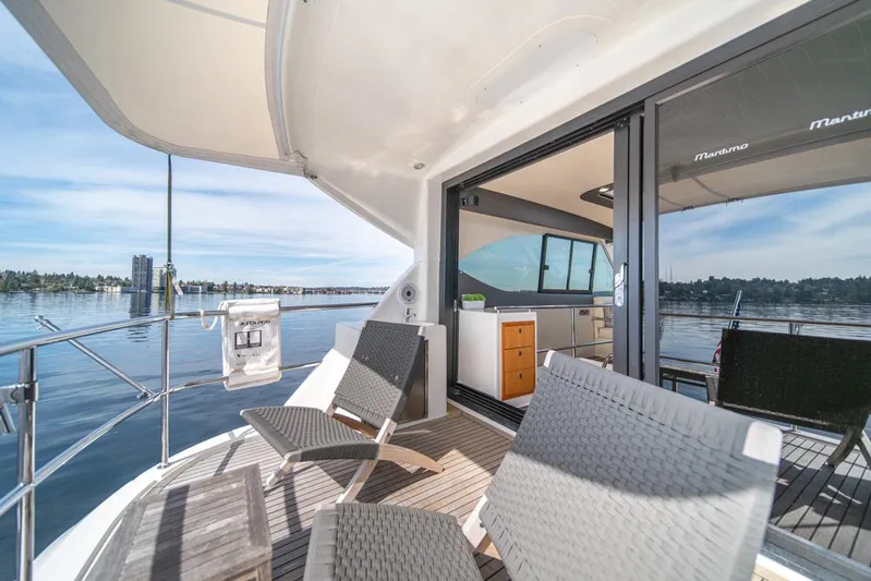 Escape Yacht Photos Pics 2013 Maritimo M58 yacht deck with chairs, open sliding doors, and scenic water view.