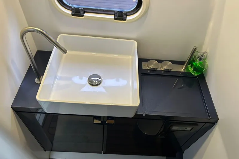 Quoq Yacht Photos Pics Modern bathroom sink with sleek faucet and green soap dispenser on black counter.