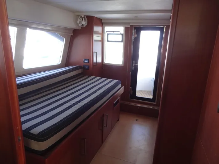 Dalliance Yacht Photos Pics 2014 Leopard 58 yacht interior cabin with striped bed and wooden furnishings.