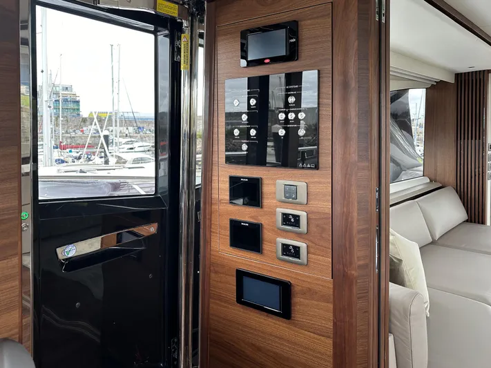 X80034 Yacht Photos Pics Control panel and seating area inside 2024 Princess X80 yacht, featuring modern wood finish.