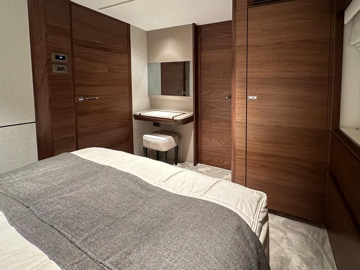 X80034 Yacht Photos Pics Luxurious cabin interior of 2024 Princess X80 yacht with elegant wood finishes and cozy bedding.