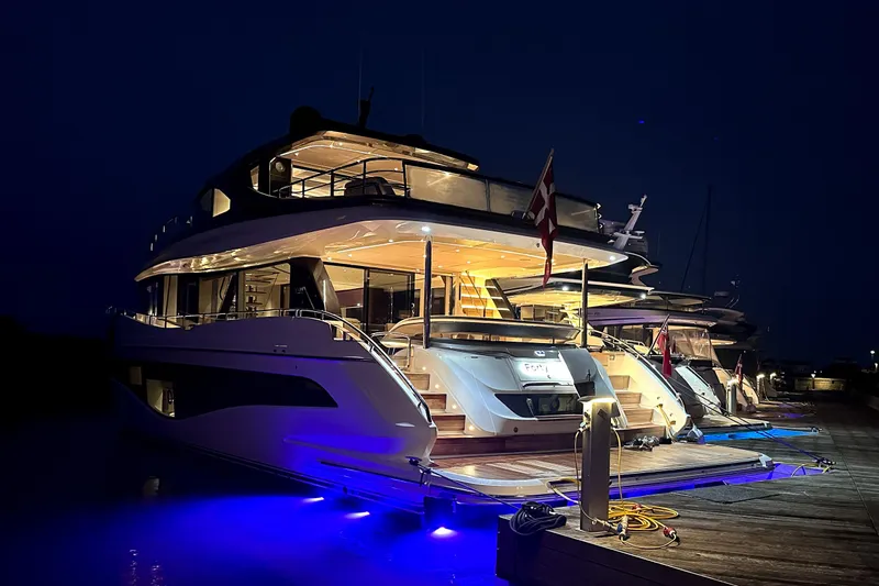 X80034 Yacht Photos Pics Luxurious 2024 Princess X80 yacht docked at night with glowing blue underwater lights.