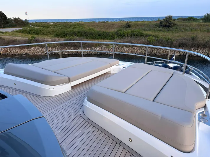 X80034 Yacht Photos Pics Luxurious 2024 Princess X80 yacht deck with sun loungers, overlooking serene coastal scenery.