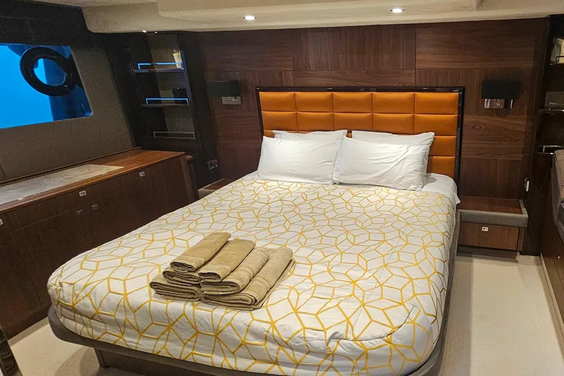  Yacht Photos Pics Luxurious bedroom interior on a 2014 Princess 64 yacht, featuring elegant bedding and wood paneling.