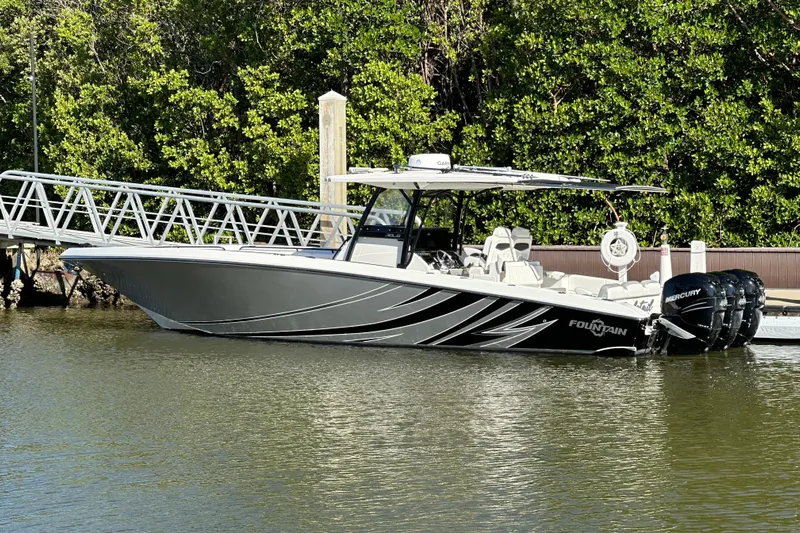  Yacht Photos Pics 2022 Fountain 38 CC LS boat docked by lush greenery.