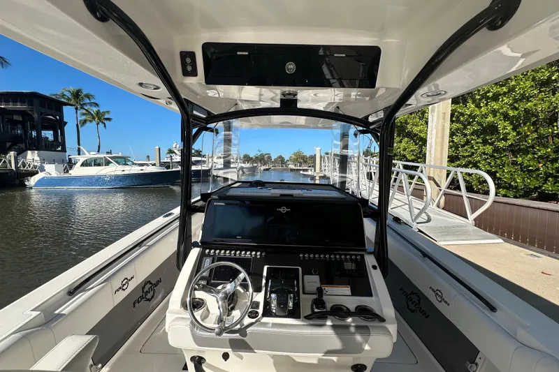  Yacht Photos Pics 2022 Fountain 38 CC LS boat interior with steering wheel and control panel at marina.