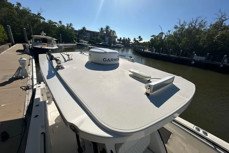  Yacht Photos Pics 2022 Fountain 38 CC LS boat docked, featuring Garmin equipment, surrounded by lush greenery.