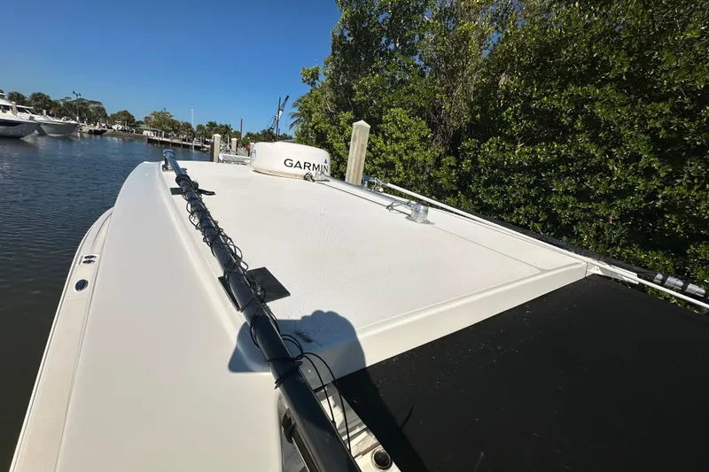  Yacht Photos Pics 2022 Fountain 38 CC LS boat docked near lush greenery and calm waters.