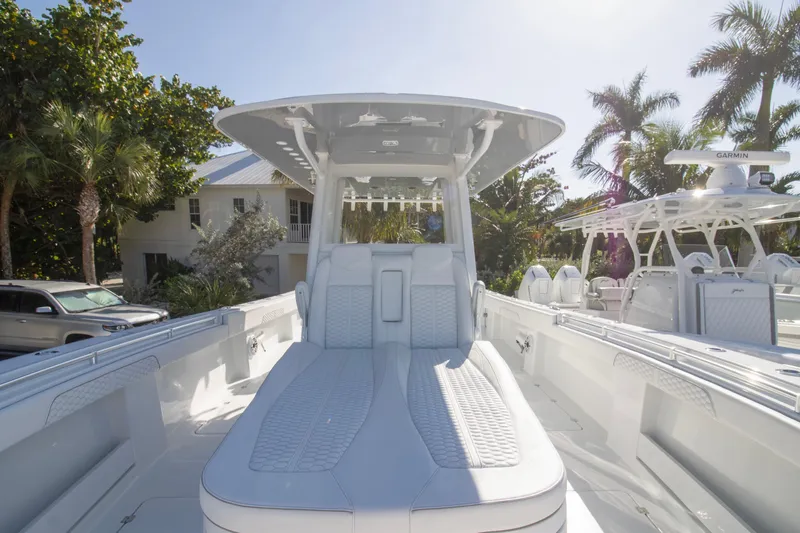  Yacht Photos Pics 2026 Invincible 36 Catamaran with sleek seating, docked near tropical foliage and modern architecture.