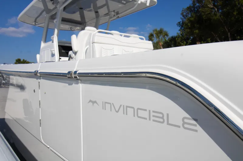  Yacht Photos Pics 2026 Invincible 36 Catamaran, sleek white design, side view with logo, clear blue sky.