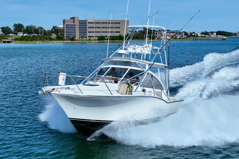 Barbara Ann Yacht Photos Pics 2001 Carolina Classic 35 Express boat cruising on blue water near a coastal building.