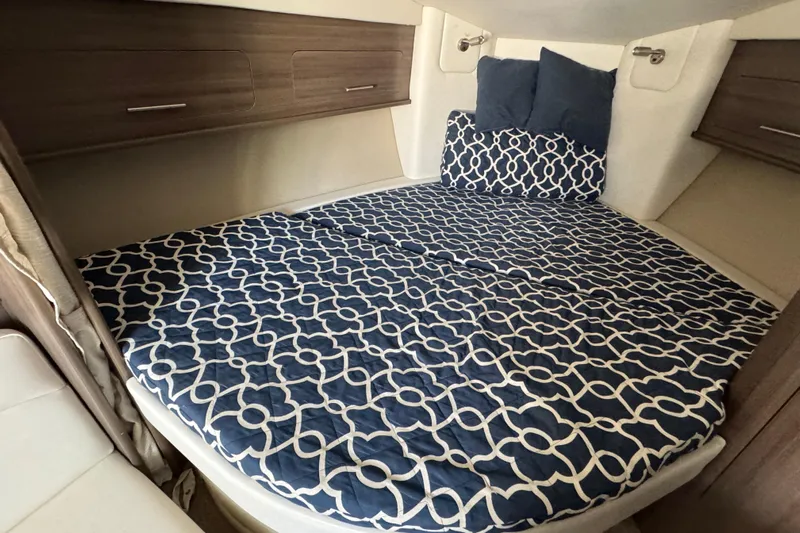  Yacht Photos Pics 2020 Rinker 320 EX cabin interior with patterned bedding and wooden storage cabinets.