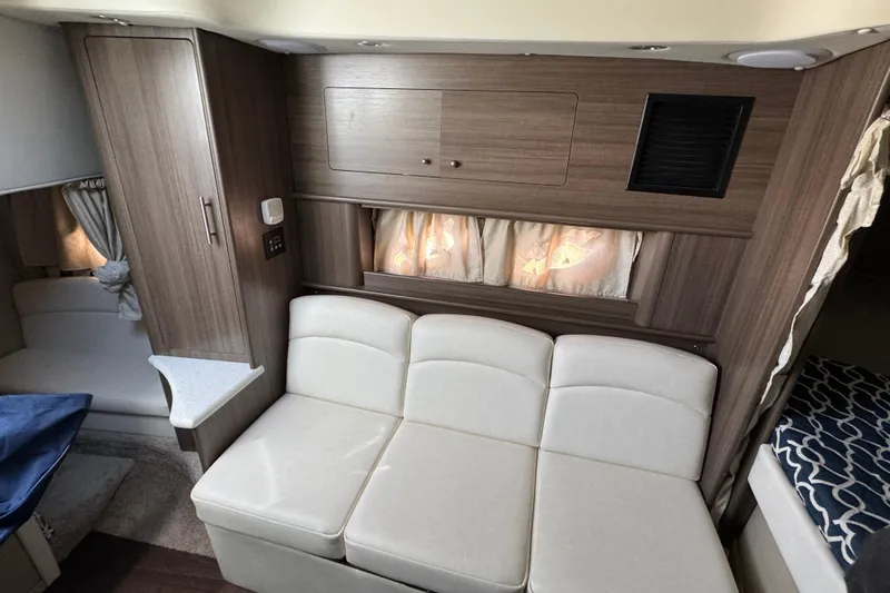 Yacht Photos Pics 2020 Rinker 320 EX interior with white seating, wood cabinetry, and cozy curtains.