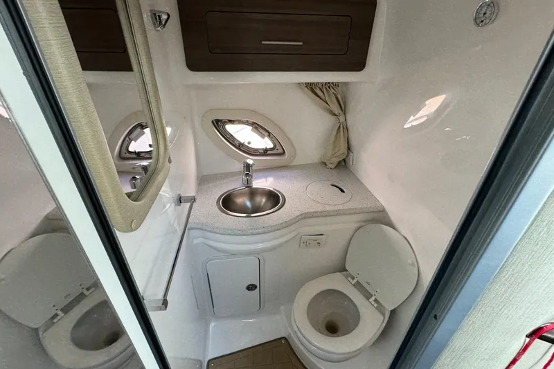  Yacht Photos Pics 2020 Rinker 320 EX boat bathroom with sink, toilet, and porthole windows.