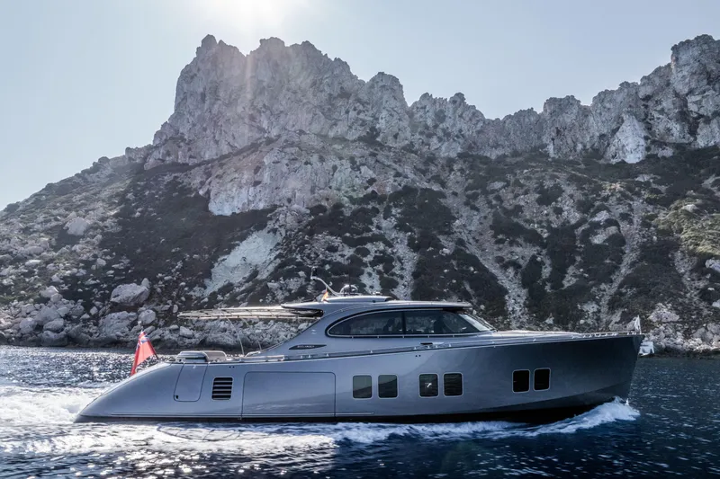 Loloma Yacht Photos Pics 2025 Zeelander 7 yacht cruising near rocky coastline under bright sun.