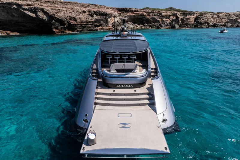 Loloma Yacht Photos Pics Luxurious 2025 Zeelander 7 yacht in clear turquoise waters near rocky coastline.