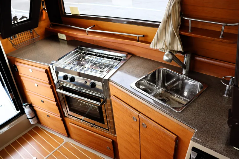 Knot Busy Yacht Photos Pics 2017 Ranger Tugs R-29 CB galley with stove, sink, and wooden cabinetry.