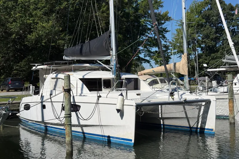 Selah Yacht Photos Pics 2010 Leopard 38 catamaran docked in a marina, surrounded by trees and other boats.