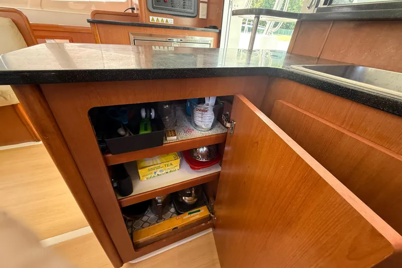 Selah Yacht Photos Pics Kitchen cabinet in a 2010 Leopard 38 yacht, featuring open shelves with various items.