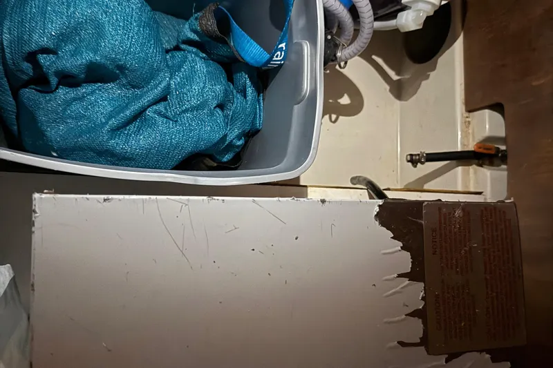 Selah Yacht Photos Pics Storage compartment in a 2010 Leopard 38, containing a blue fabric and plumbing components.