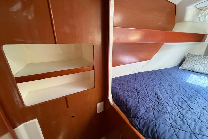 Selah Yacht Photos Pics Cozy cabin interior of 2010 Leopard 38 with wooden shelves and blue bedding.