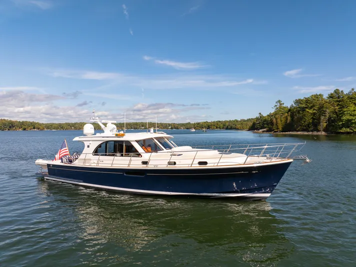 Mystique Yacht Photos Pics 2014 Grand Banks 50 Eastbay SX yacht cruising on a serene lake under a clear blue sky.