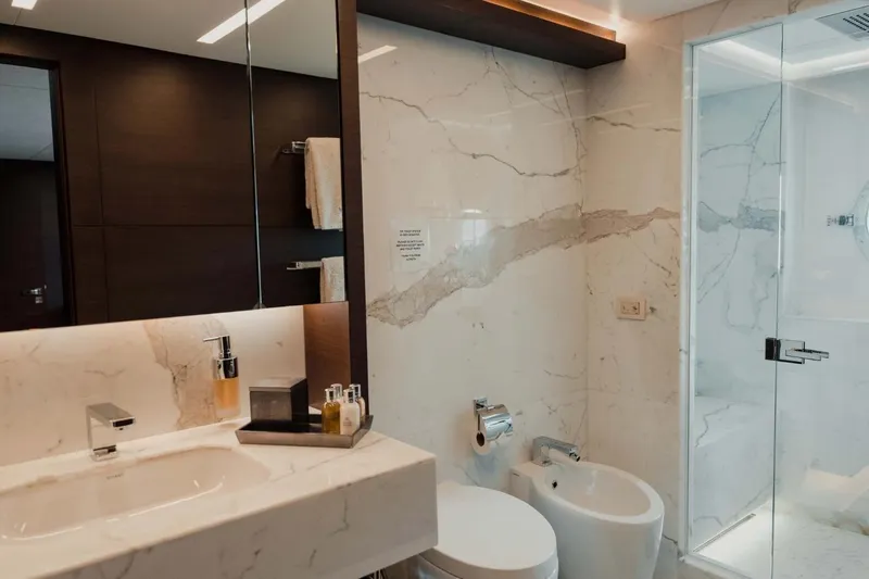  Yacht Photos Pics Luxurious bathroom with marble walls, modern fixtures, and glass shower in a Majesty 125 yacht.