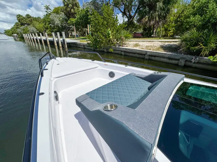  Yacht Photos Pics 2024 Axopar 37 Sun Top boat with cushioned seating, docked by lush greenery.