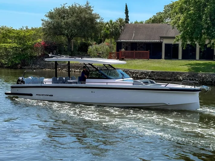  Yacht Photos Pics 2024 Axopar 37 Sun Top cruising on a scenic river with lush greenery.