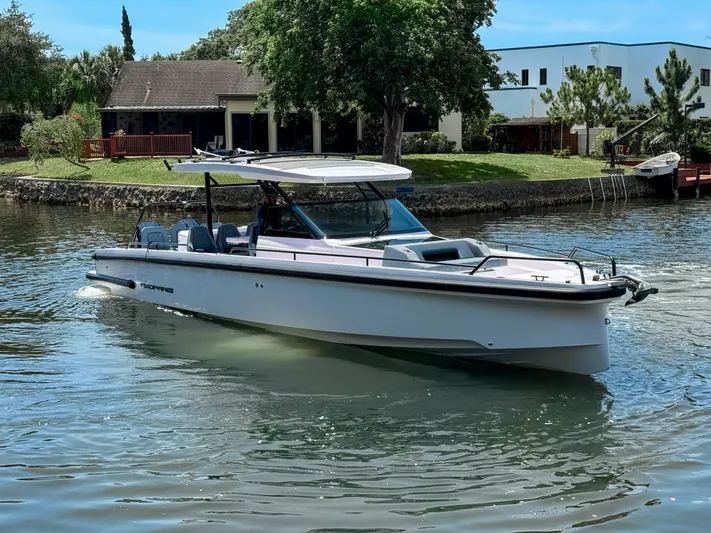  Yacht Photos Pics 2024 Axopar 37 Sun Top boat cruising on a calm river near a residential area.