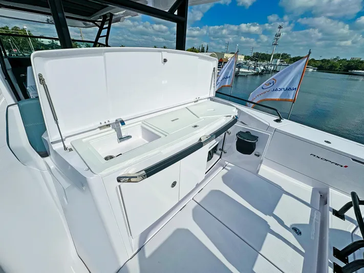 Yacht Photos Pics 2024 Axopar 37 Sun Top boat with outdoor sink and storage, docked by the water.
