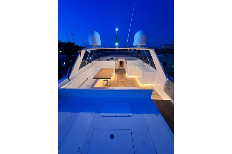 Yacht Photos Pics Luxurious 1987 Magnum 63 yacht deck illuminated at dusk, featuring elegant seating and wooden table.