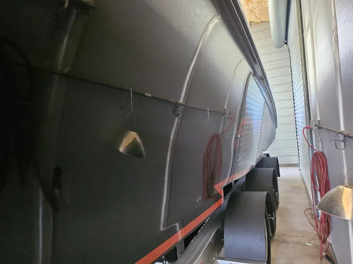  Yacht Photos Pics 2021 Statement 350 Open boat in storage, side view with trailer wheels visible.