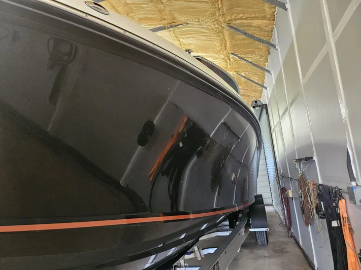  Yacht Photos Pics 2021 Statement 350 Open boat in storage, sleek black hull with orange stripe.