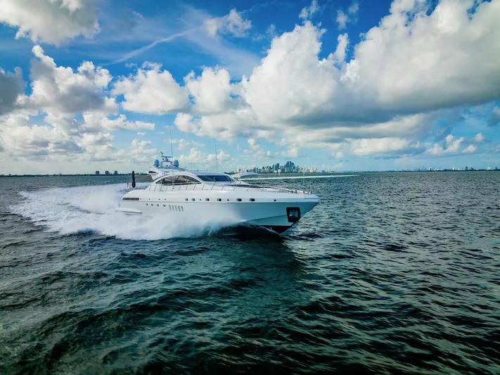 Houdini Yacht Photos Pics Luxury 2007 Mangusta 92 yacht cruising on open water under a vibrant sky.
