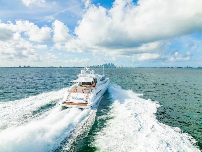 Houdini Yacht Photos Pics Mangusta 92 yacht cruising on open water, 2007 model, with city skyline in background.