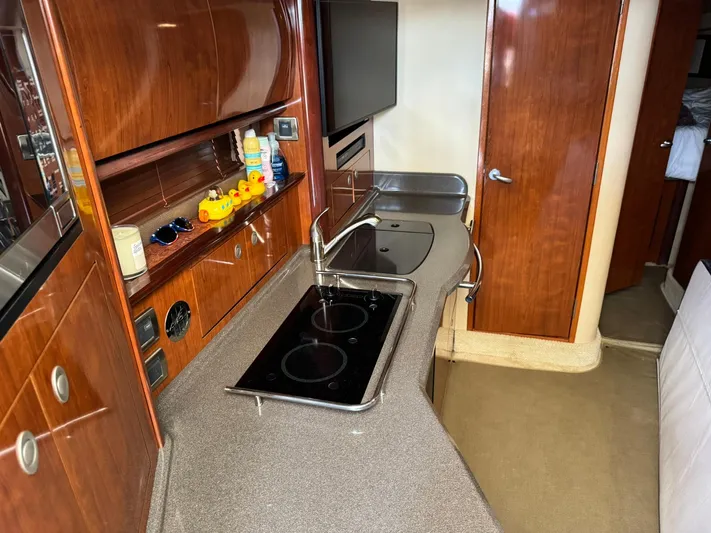 Yacht Photos Pics 2004 Sea Ray 390 Sundancer kitchen with stove, sink, and wooden cabinetry.
