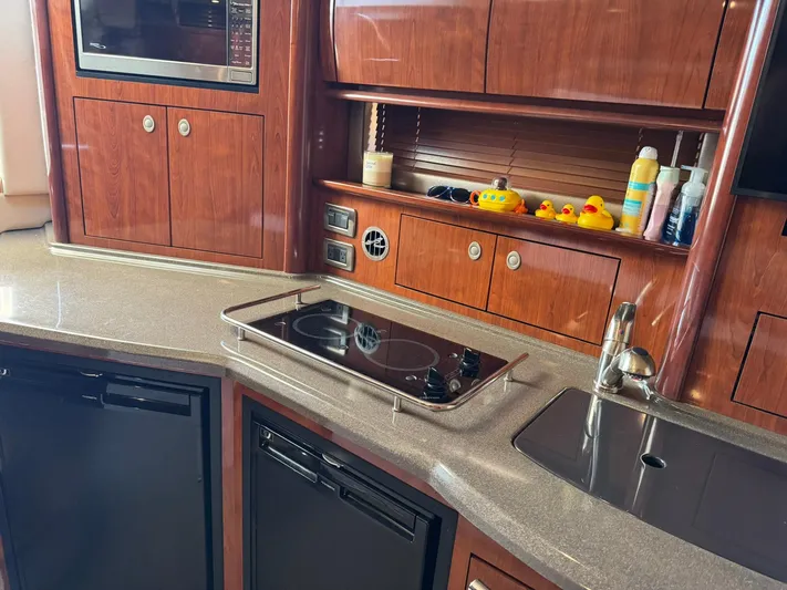  Yacht Photos Pics Interior of 2004 Sea Ray 390 Sundancer yacht kitchen with stove, sink, and wooden cabinets.