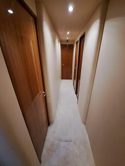 Mary Rose Yacht Photos Pics Interior hallway of 2006 Hatteras 68 Convertible yacht with wooden doors and carpeted floor.