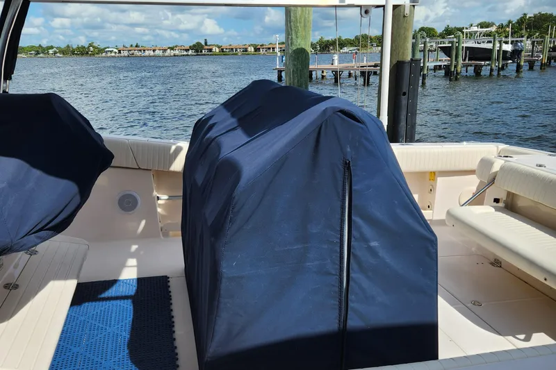  Yacht Photos Pics 2012 Grady-White Canyon 336 boat interior with covered equipment, docked by the water.