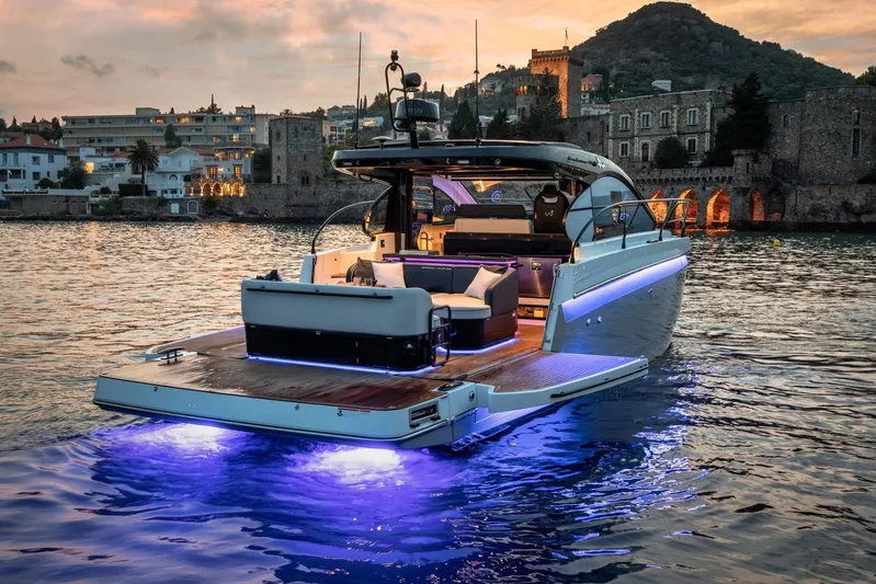 On Order Yacht Photos Pics 2026 Beneteau Gran Turismo 40 yacht illuminated on water at sunset, near historic buildings.