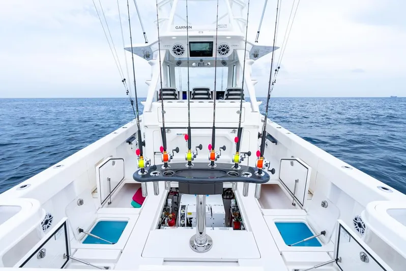 Yacht Photos Pics 2024 SeaVee 450z fishing boat with rods, spacious deck, and ocean backdrop.