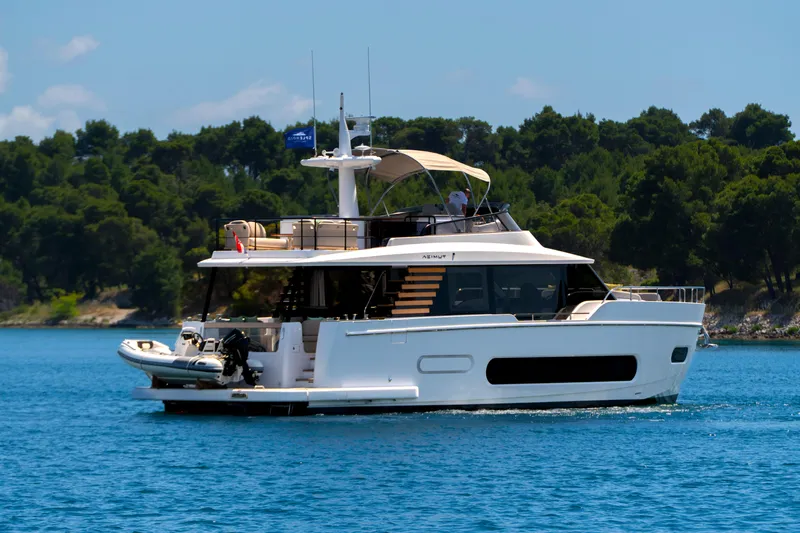 Olivia Yacht Photos Pics 2025 Azimut Magellano 60 yacht cruising on a serene blue sea with lush green trees.
